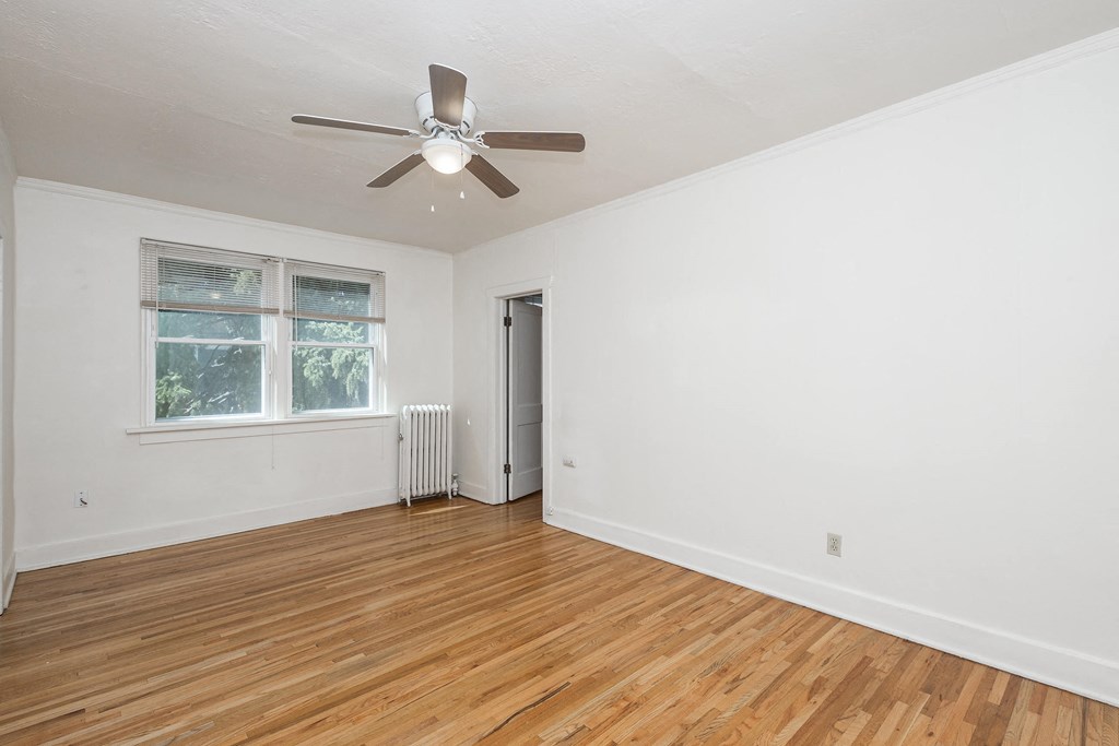 A room with a ceiling fan and a window with a view of trees.