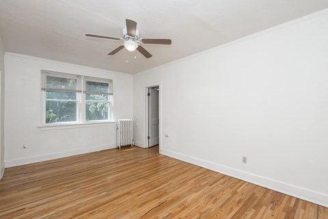 A room with a ceiling fan and a window with a view of trees.