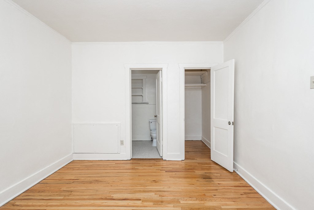 A room with white walls and wooden floors with two open doors.