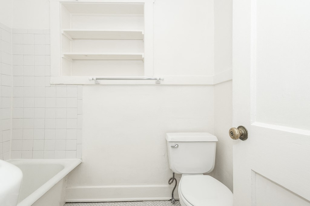 A white toilet sits next to a white bathtub in a small bathroom.