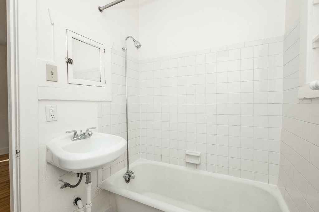 A white bathroom with a sink, tub, and shower.
