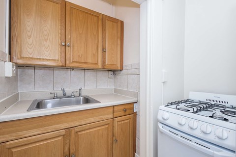 A kitchen with wooden cabinets and a white stove.