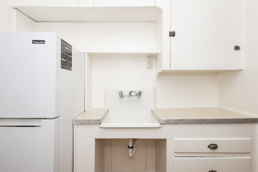 A white fridge and sink in a small kitchen.