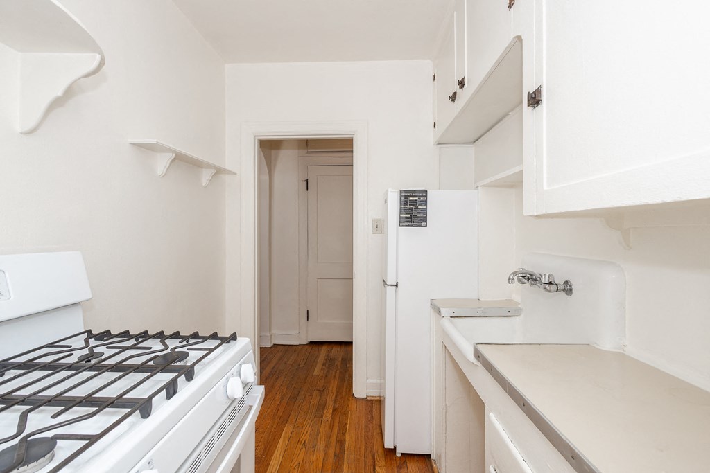 A white kitchen with a stove and a sink.