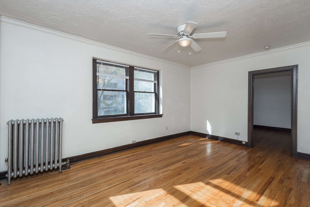 A room with a ceiling fan and a radiator on the wall.
