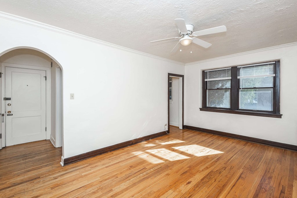 A room with a white ceiling fan and a window with black frames.
