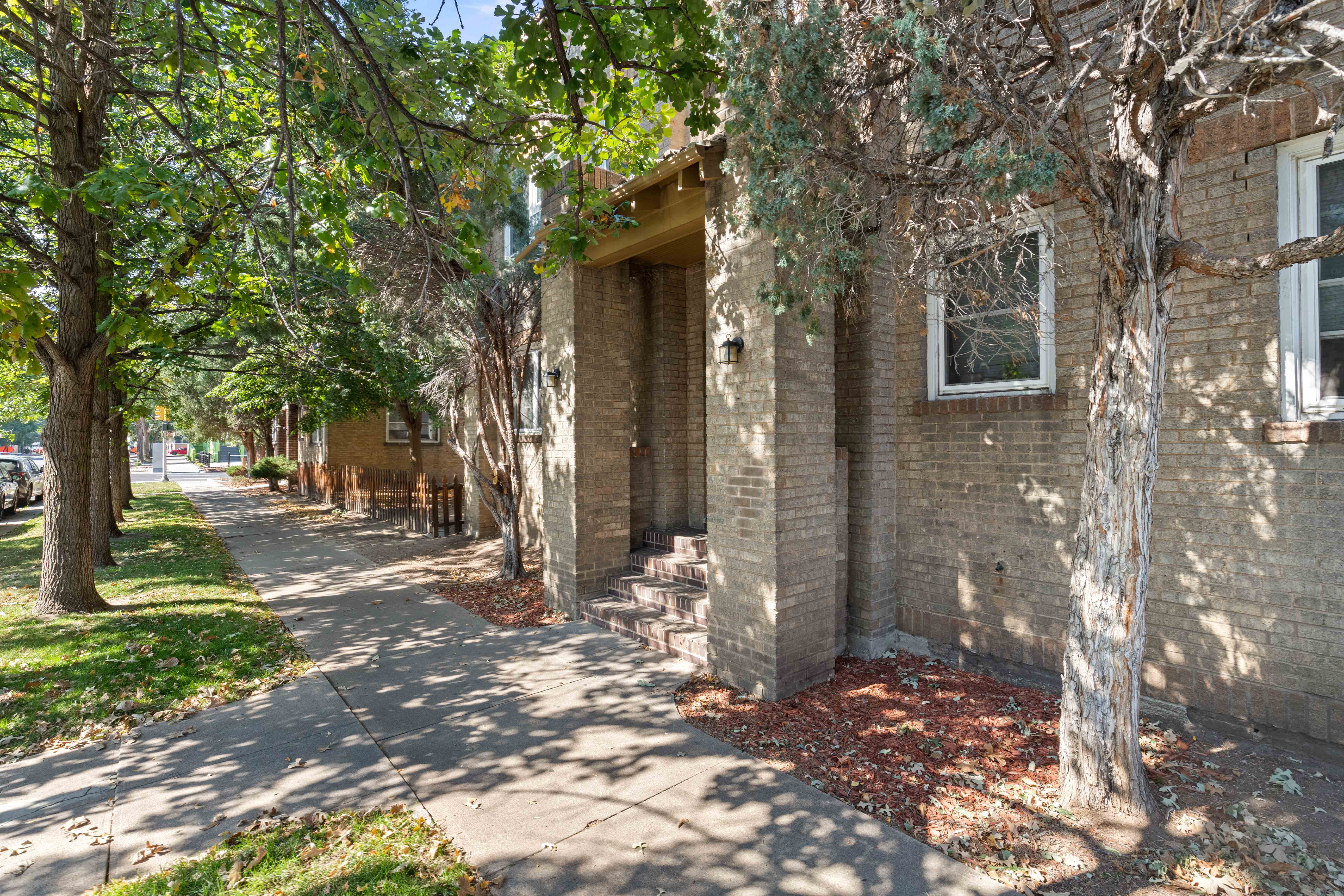 a brick building with trees and a sidewalk