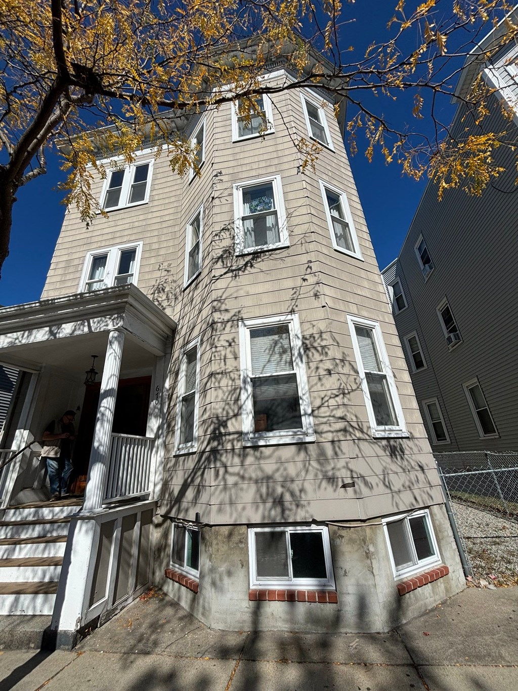 A tall building with a balcony and a tree in front of it.
