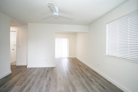 an empty living room with wood floors and a ceiling fan