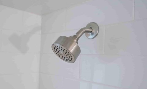 a shower head in a white tiled bathroom