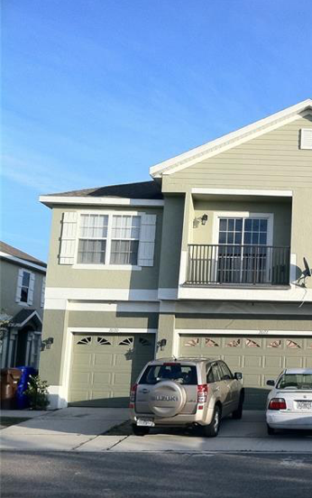 A two-story house with a garage and two cars parked in front.