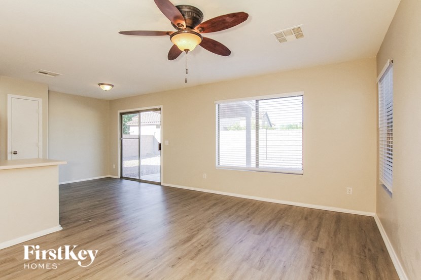 the living room and dining room of an empty house with a ceiling fan