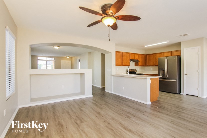 an empty kitchen and living room with a ceiling fan