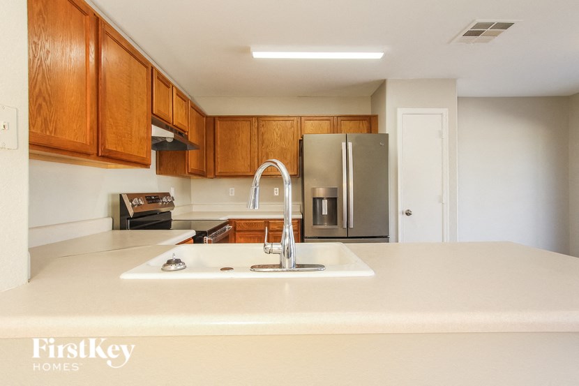 a kitchen with white countertops and wooden cabinets and a stainless steel refrigerator