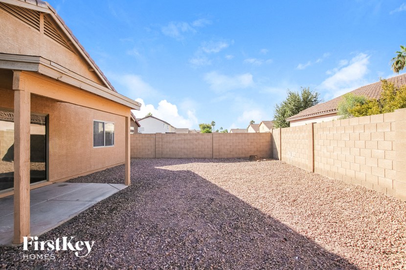 a backyard with a brick fence and a gravel driveway