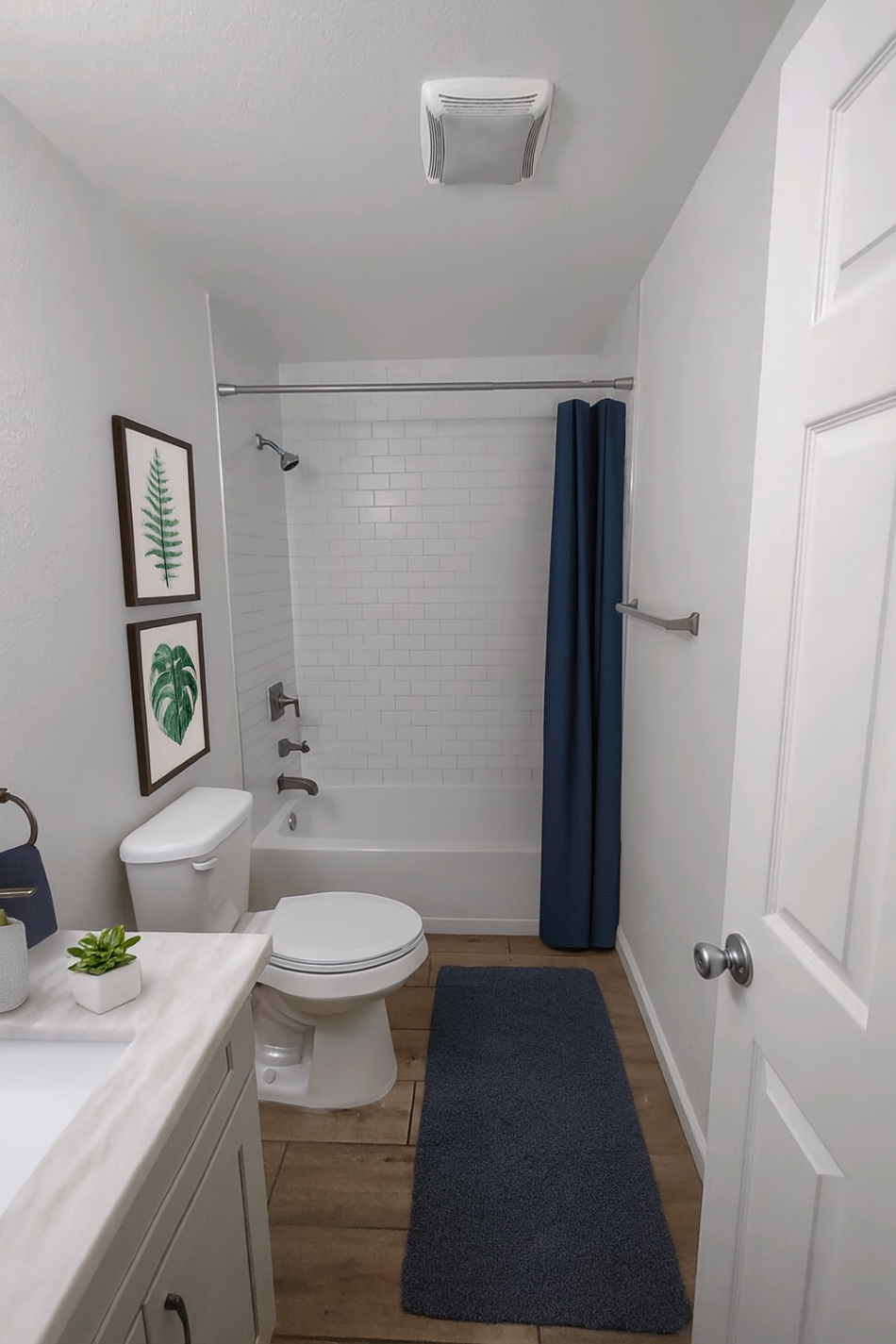 A white toilet with a white sink and a white bathtub with a blue shower curtain.