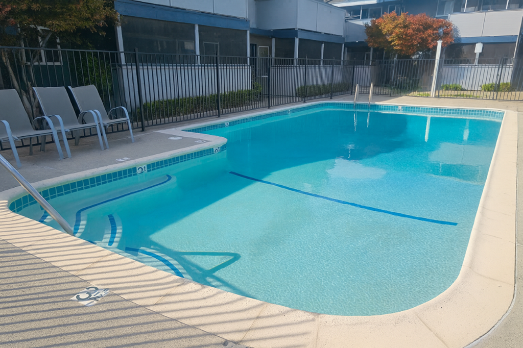 A small pool with a brownish floor and a white fence.