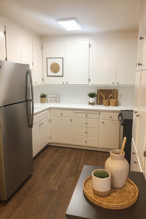 A kitchen with a refrigerator, wooden table, and white cabinets.