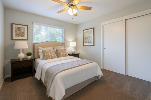 A bedroom with a large bed and a ceiling fan.