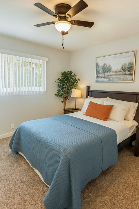 A bedroom with a bed, a ceiling fan, and a painting on the wall.