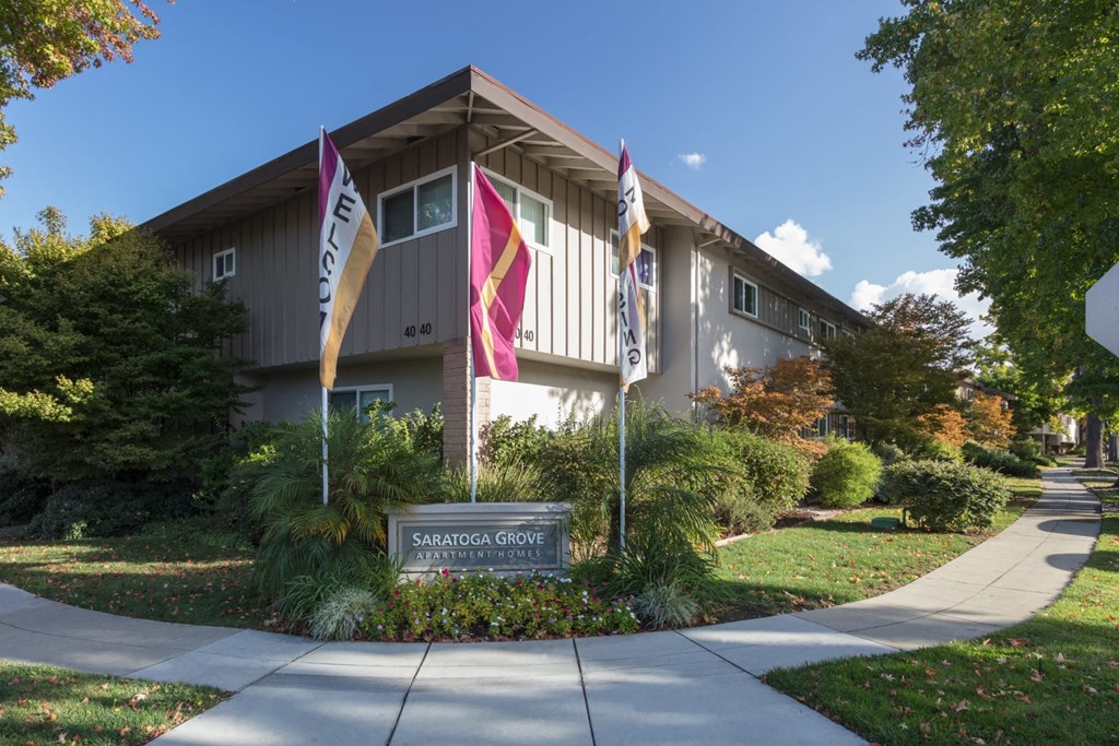 A Saratoga Grove sign is in front of a building with flags on either side.