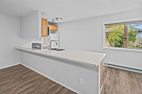 A kitchen with a white countertop and wooden cabinets.