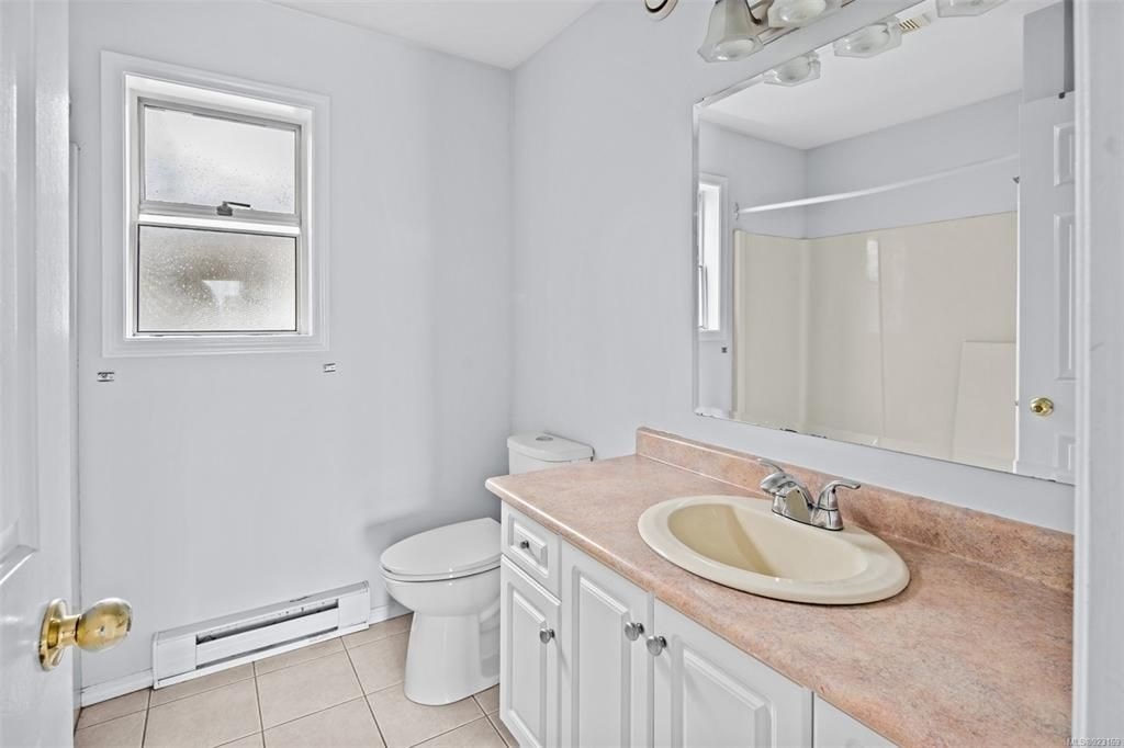 A bathroom with a toilet, sink, and mirror.