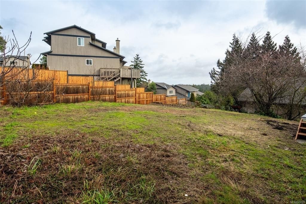 A house with a brown fence and a tree in the front yard.