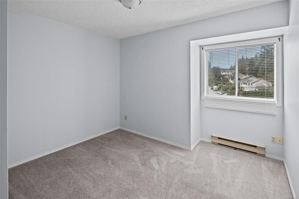A room with a window and a carpeted floor.