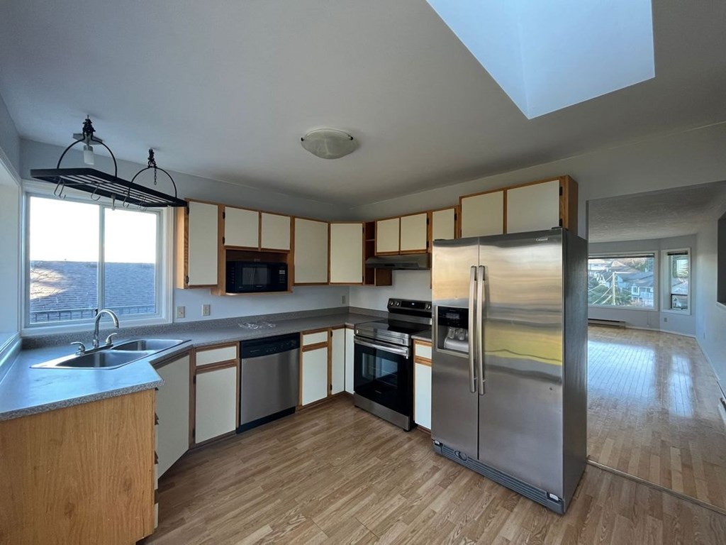 A kitchen with wooden floors and stainless steel appliances.