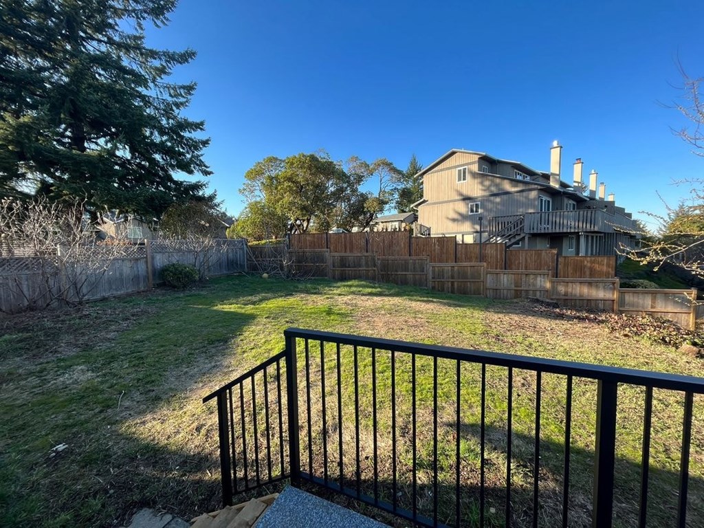 A house with a fence and a tree in the backyard.