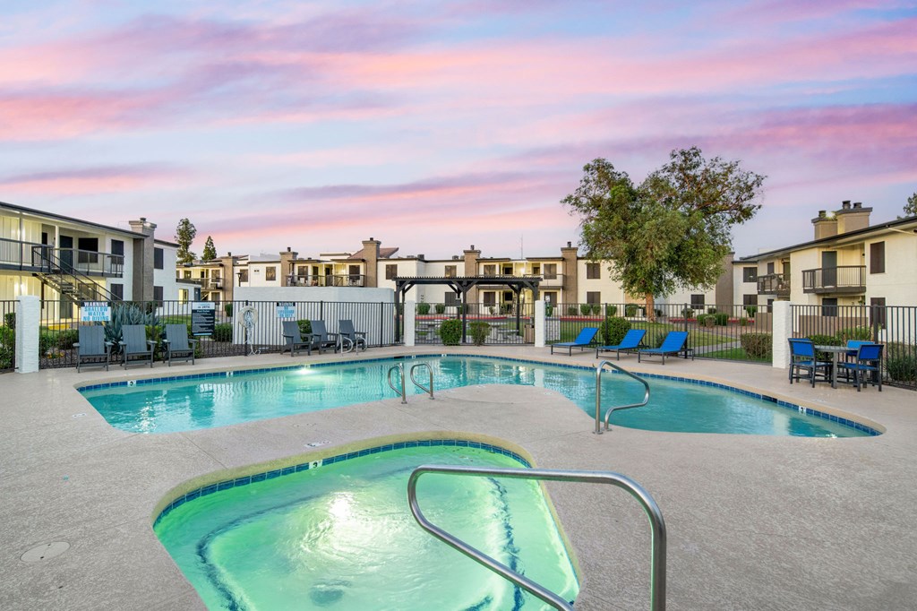 A swimming pool surrounded by chairs and buildings.