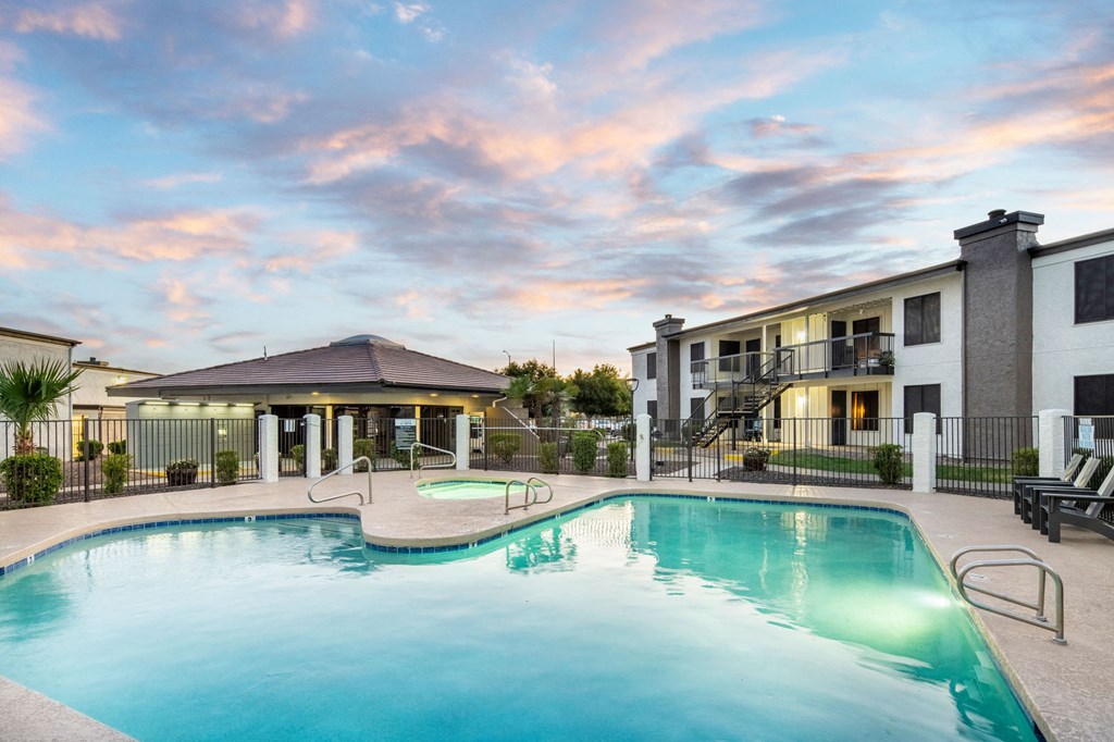 A swimming pool in front of a building with a sunset in the background.
