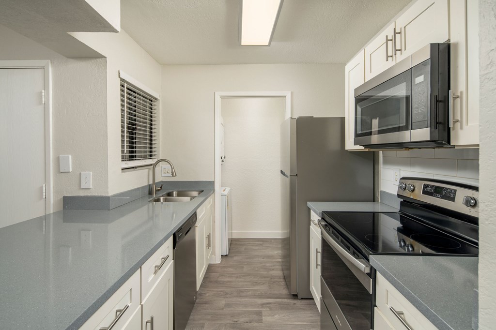 A kitchen with a refrigerator, oven, and microwave.