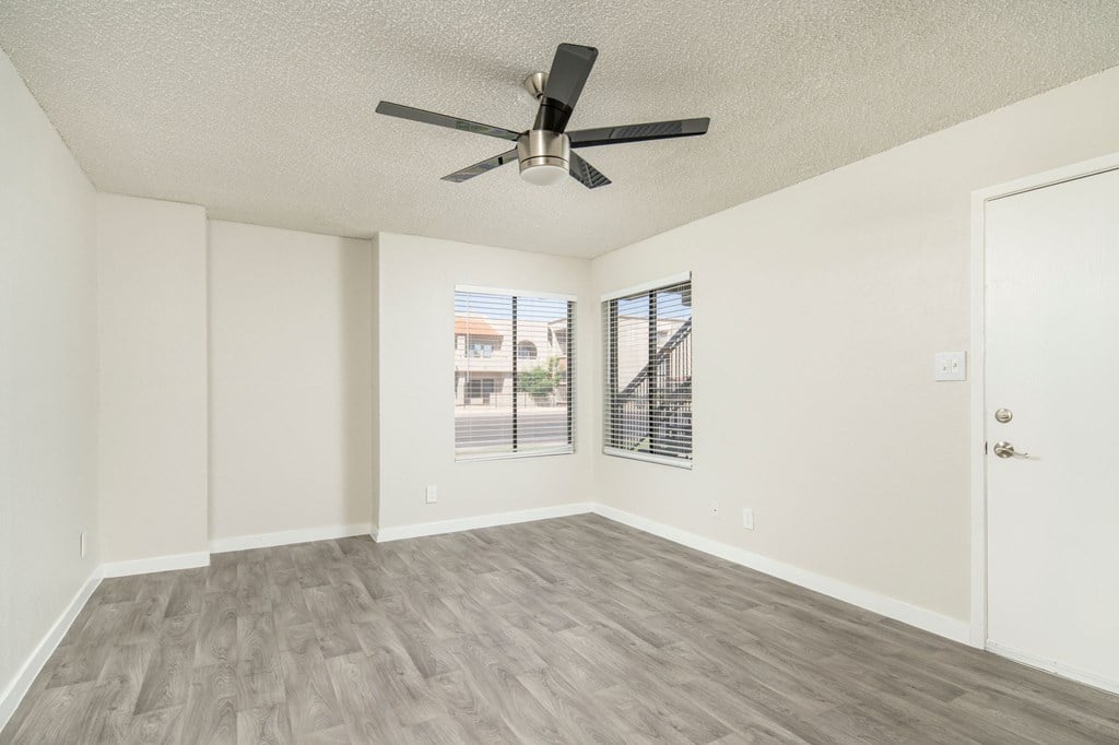 A room with a ceiling fan and a window with blinds.