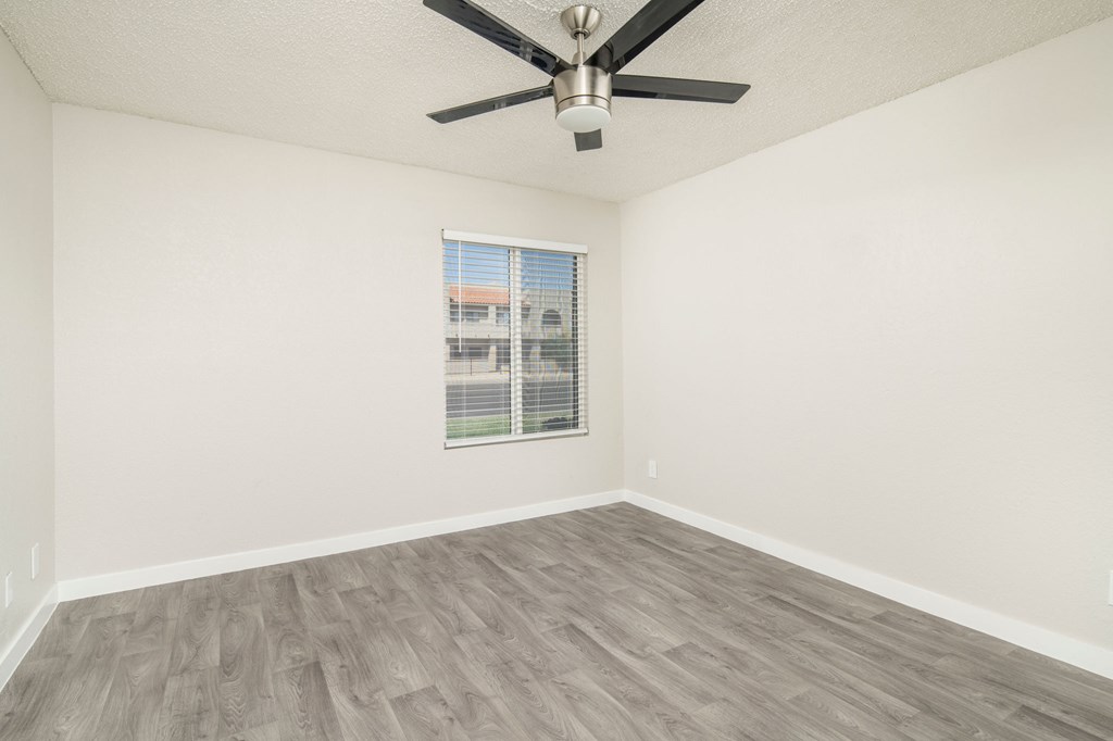 A room with a ceiling fan and a window with blinds.