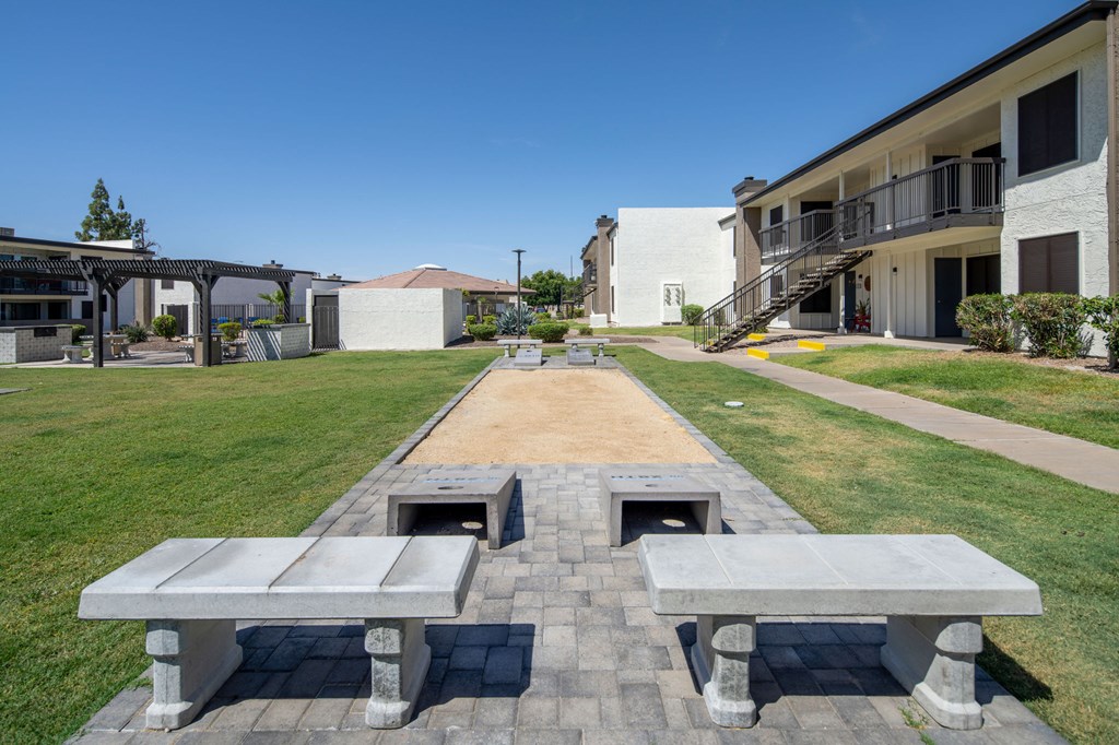 A long concrete bench with two smaller benches on the ends sits in the middle of a grassy area.