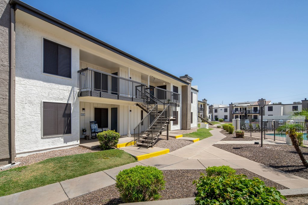 A white building with a balcony and stairs leading to the entrance.