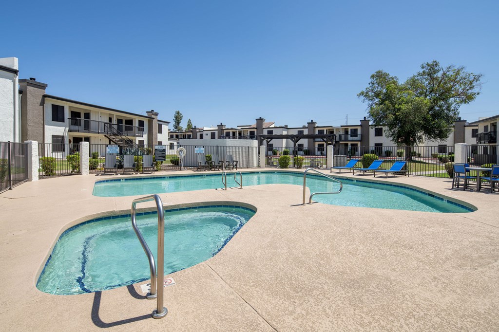 A swimming pool with a diving board in the middle of a concrete pool area.