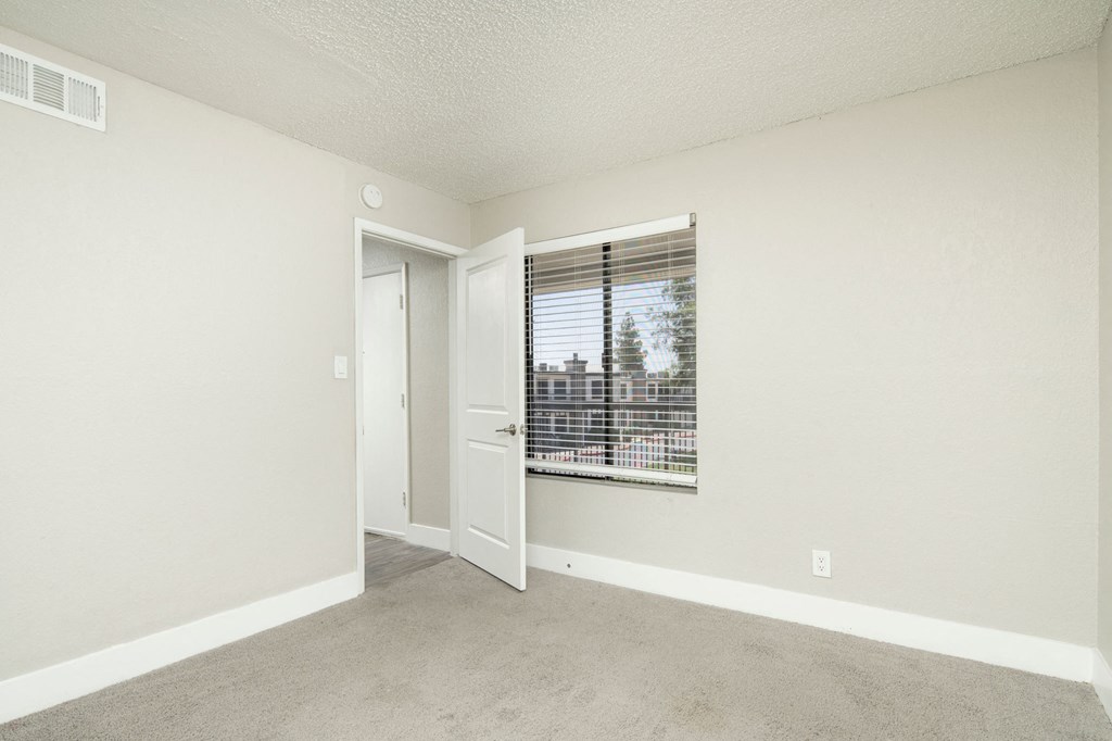 A room with a carpeted floor and a window with blinds.