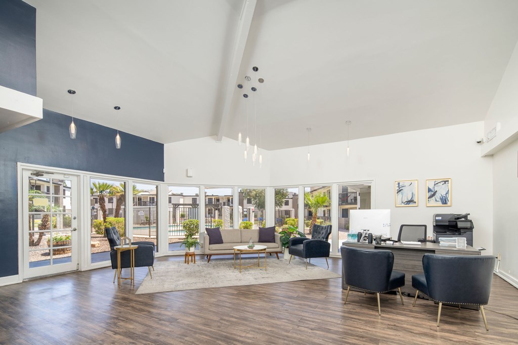 A room with a desk and chairs in front of a window.