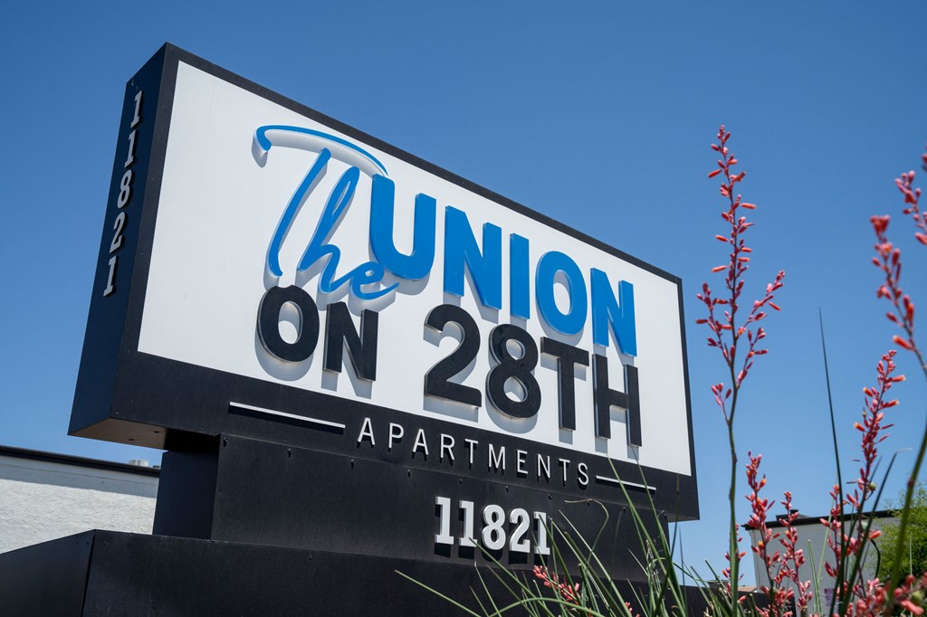 A sign for The Union on 28th Apartments with a blue sky in the background.