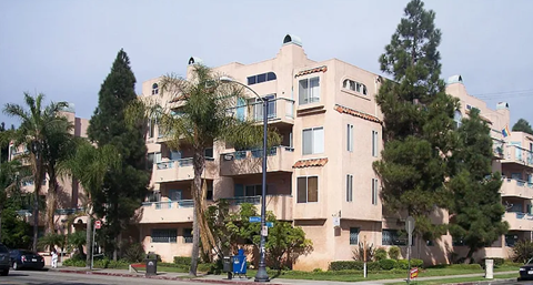an apartment building with palm trees in front of it