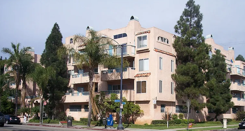 A large beige building with a balcony on the second floor.