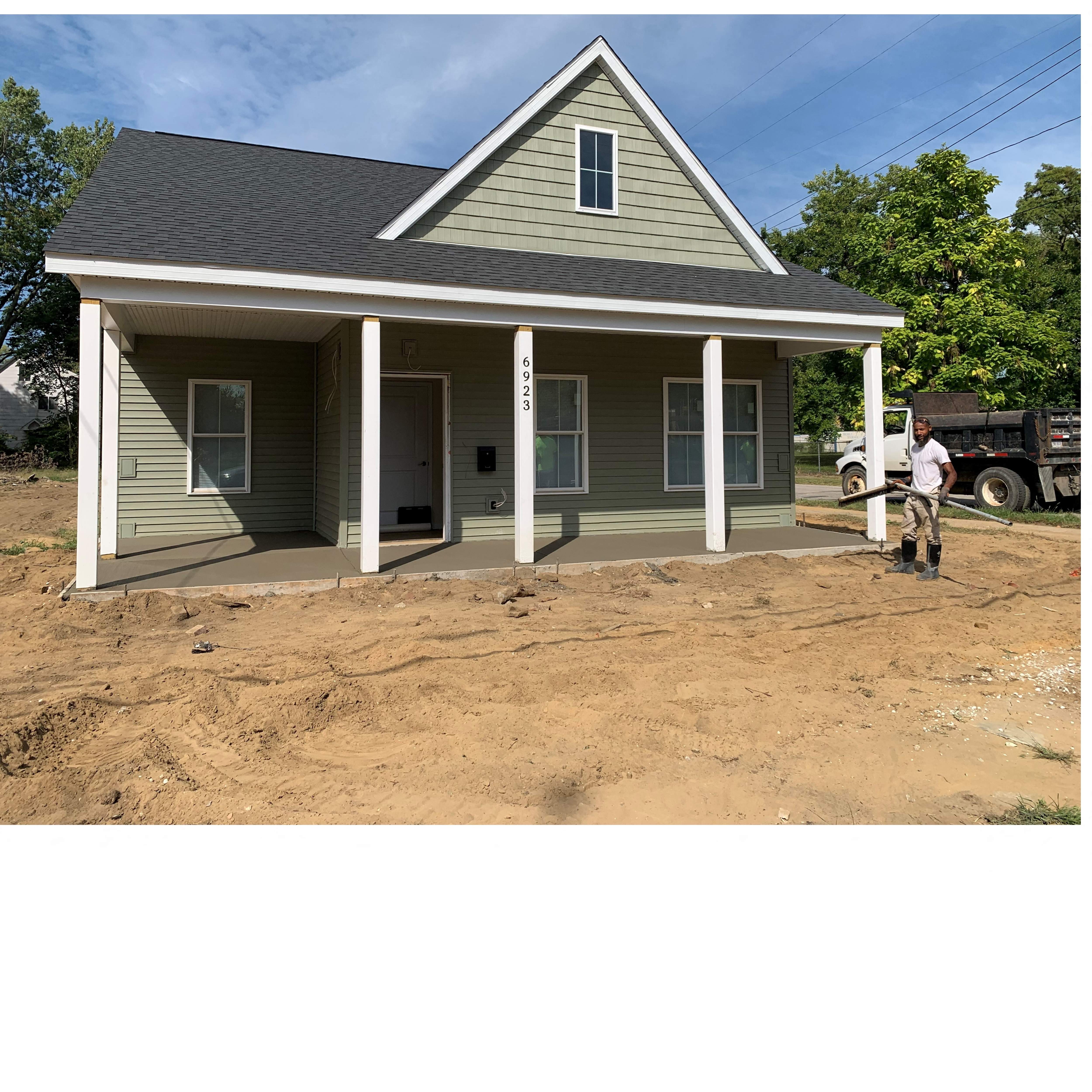 A house under construction with a man standing in front.
