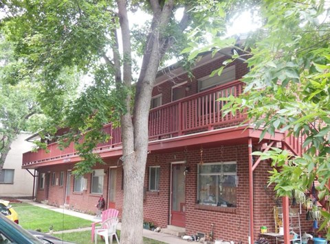a red brick house with a balcony and a tree