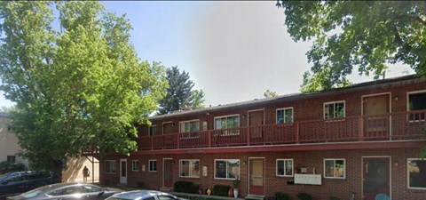 a red brick apartment building with cars parked in front of it