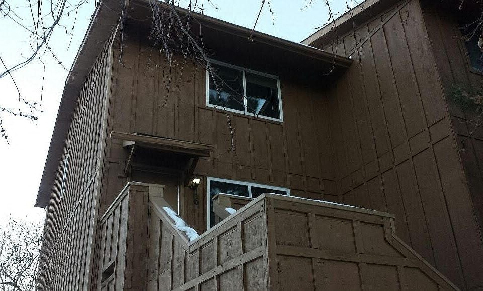 A brown wooden house with a window and a door.
