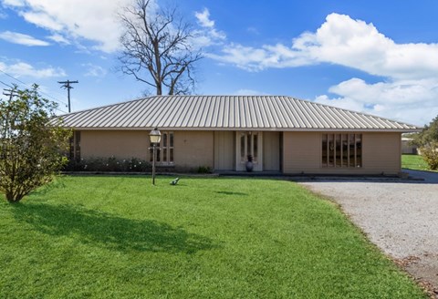 A house with a grey roof and a green lawn in front.