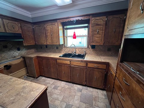 A kitchen under construction with wooden cabinets and a window.
